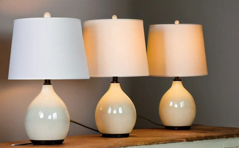 Four table lamps lined up on a sideboard: a brass column lamp, a paper shade lamp, a metal clip lamp and a ceramic base lamp